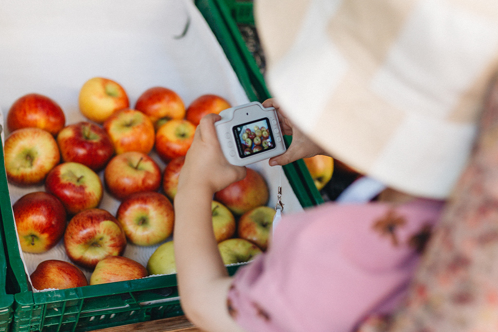 Petite fille photographiant des pommes à l'aide de son appareil photo enfant hoppstar expert