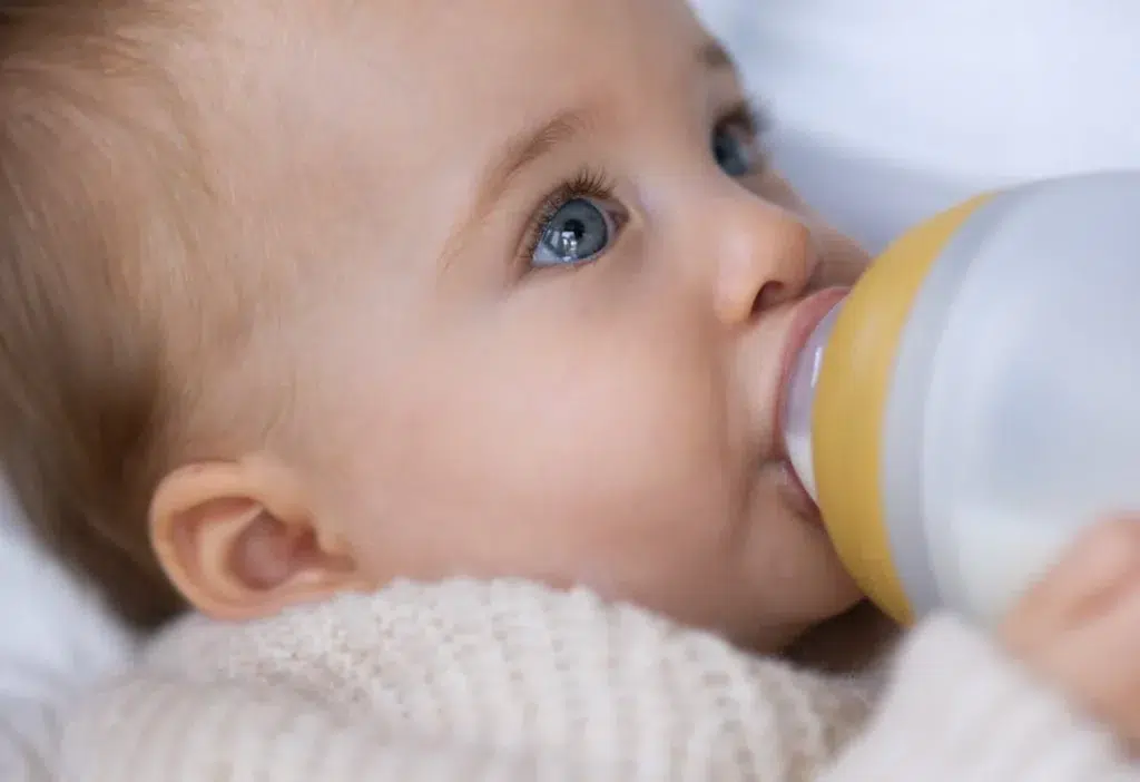 Bébé aux grands yeux bleu buvant son biberon Elhée